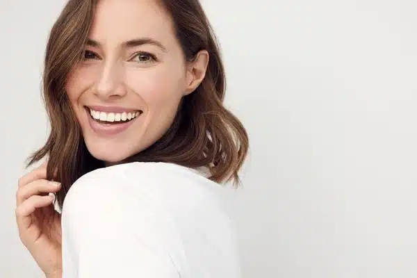 Close-up of a happy young woman smiling and looking over her shoulder